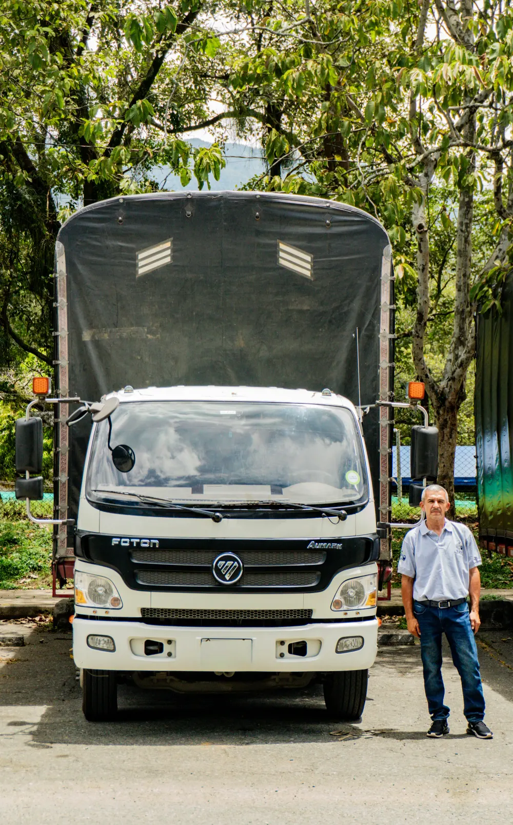 Un integrante del equipo posa junto al frente de un camión de la flota